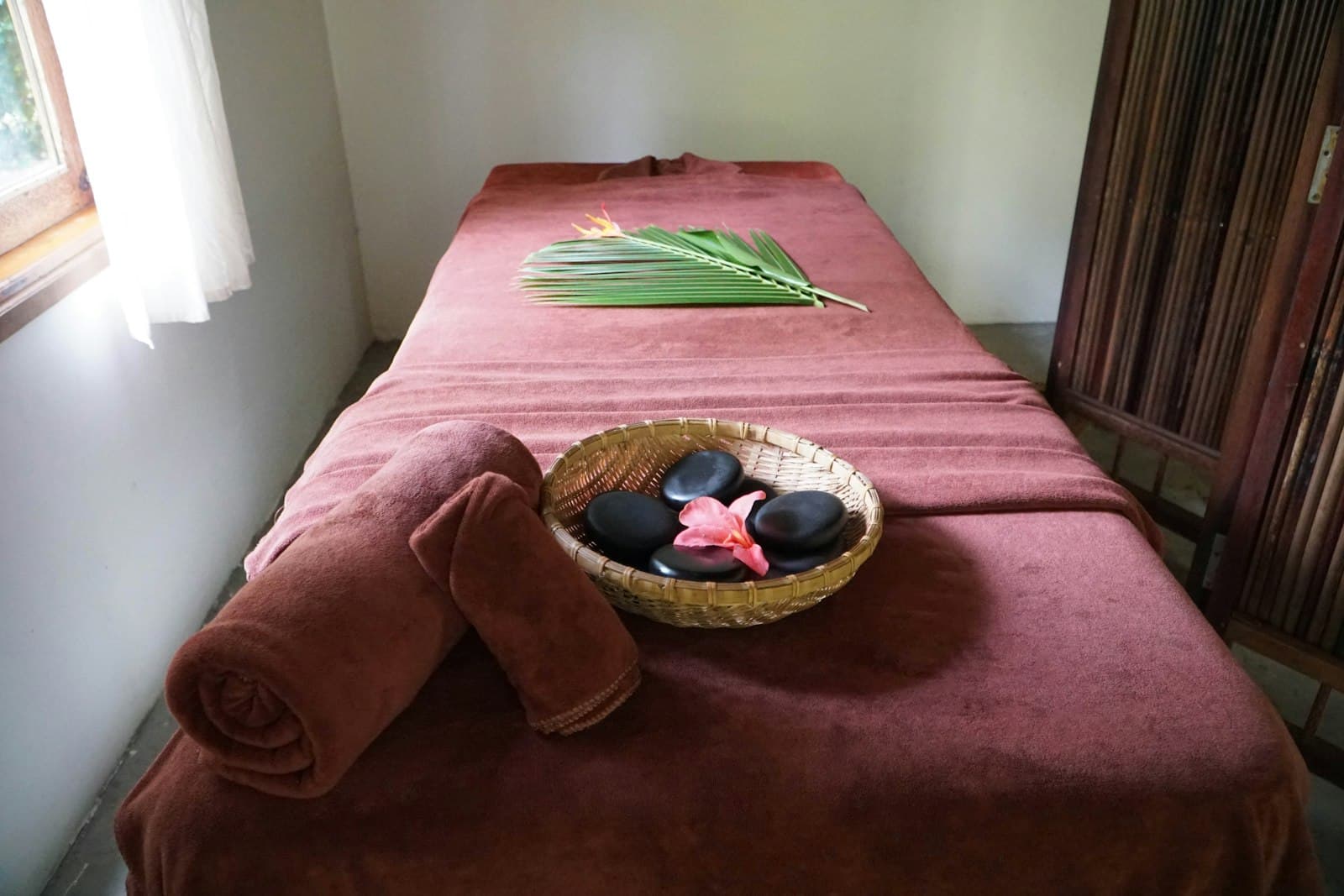 A calm, warmly lit treatment room with a towel-dressed massage bed ready