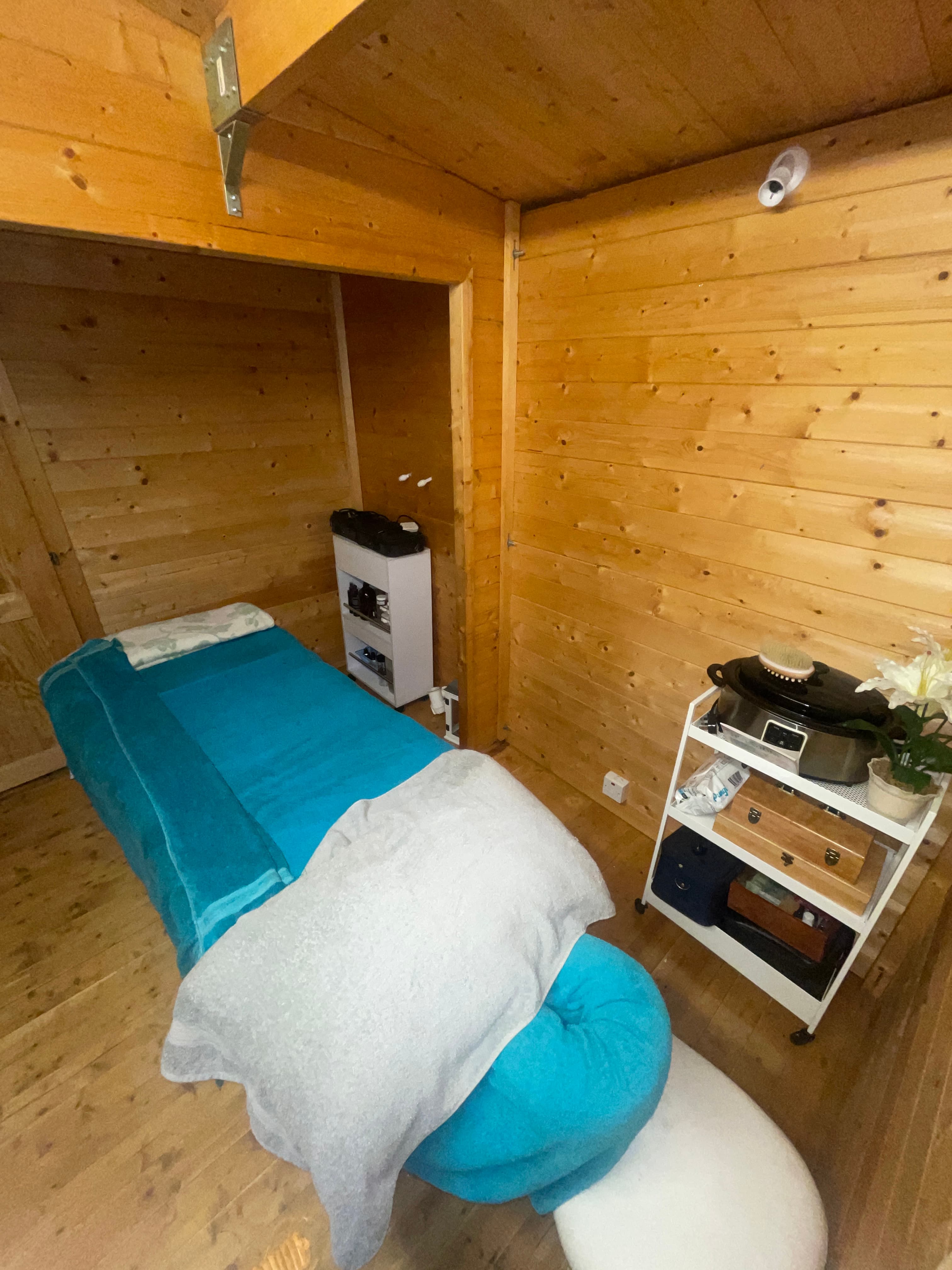 Inside the log cabin studio: the massage table made up with towels, ready for an appointment