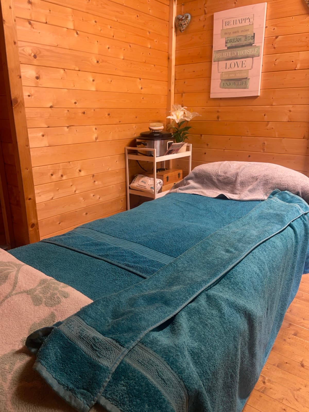 The warm, wood-lined treatment room inside the log cabin at Essential Massage, with the massage bed made up in towels